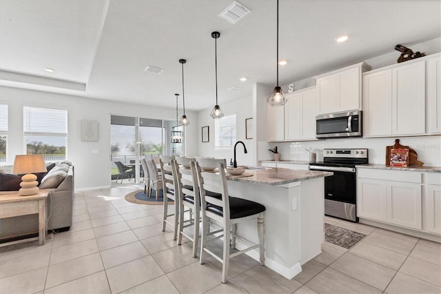 kitchen featuring light tile patterned floors, a sink, visible vents, appliances with stainless steel finishes, and decorative backsplash