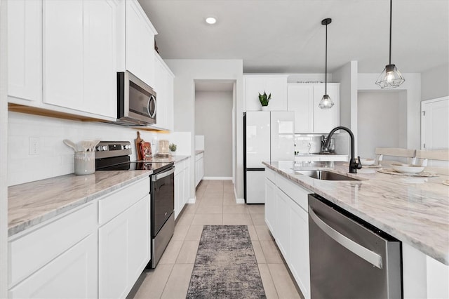 kitchen with light tile patterned floors, white cabinets, a sink, stainless steel appliances, and backsplash