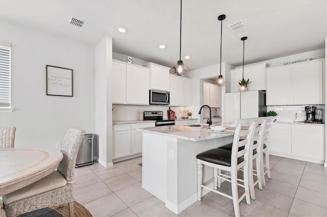 kitchen with stainless steel appliances, visible vents, a kitchen island with sink, a sink, and light tile patterned flooring