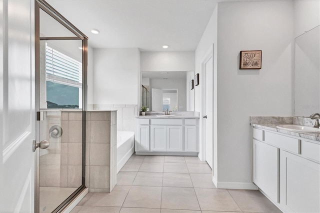 bathroom with tile patterned floors, two vanities, a stall shower, a sink, and a bath