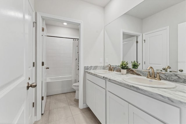 full bath featuring double vanity, a sink, toilet, and tile patterned floors