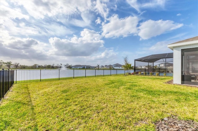 view of yard with glass enclosure, a water view, and fence private yard