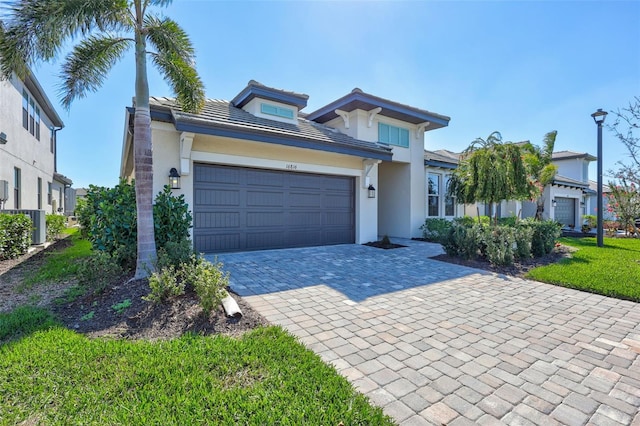 view of front facade featuring a garage, decorative driveway, and stucco siding