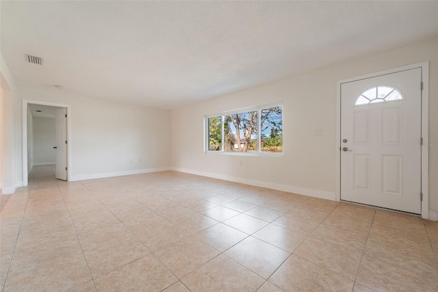 entrance foyer with light tile patterned floors, a textured ceiling, visible vents, and baseboards