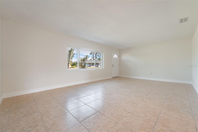 empty room featuring light tile patterned floors, visible vents, and baseboards