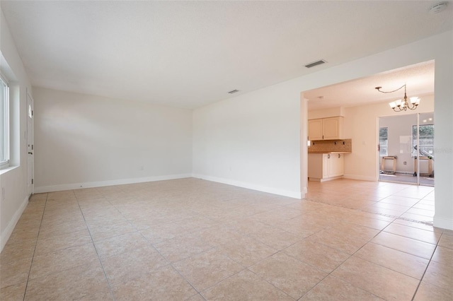 spare room featuring an inviting chandelier, visible vents, light tile patterned floors, and baseboards