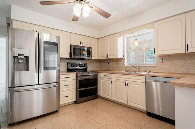 kitchen with light tile patterned floors, tasteful backsplash, light countertops, appliances with stainless steel finishes, and a sink