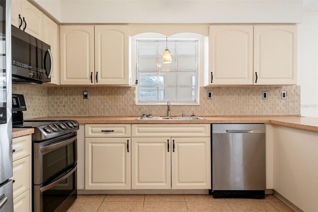 kitchen featuring light tile patterned floors, appliances with stainless steel finishes, a sink, light countertops, and backsplash