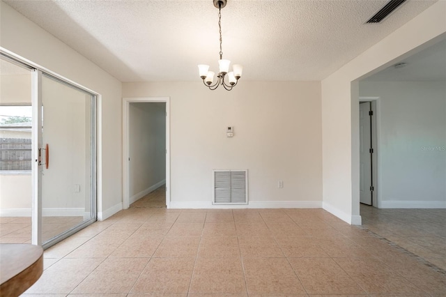 unfurnished room featuring baseboards, a textured ceiling, visible vents, and an inviting chandelier