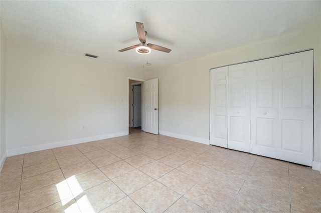 unfurnished bedroom featuring light tile patterned flooring, a ceiling fan, visible vents, baseboards, and a closet