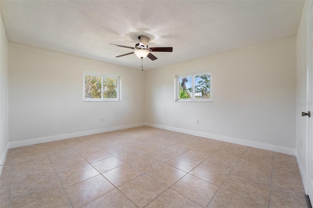 spare room featuring baseboards, a textured ceiling, a ceiling fan, and a wealth of natural light