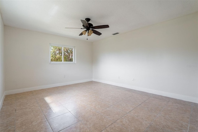 spare room featuring a textured ceiling, a ceiling fan, visible vents, and baseboards