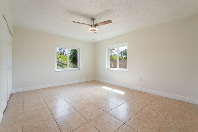 unfurnished room featuring a healthy amount of sunlight, light tile patterned floors, and ceiling fan