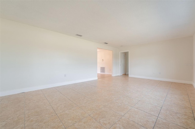 unfurnished room featuring visible vents, a textured ceiling, baseboards, and light tile patterned floors