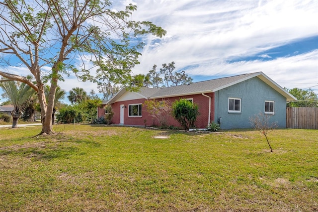 view of front of house featuring brick siding, a front yard, and fence