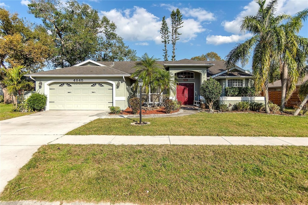 view of front of property featuring a front yard, driveway, an attached garage, and stucco siding