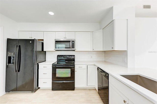 kitchen with tasteful backsplash, visible vents, light countertops, black appliances, and white cabinetry