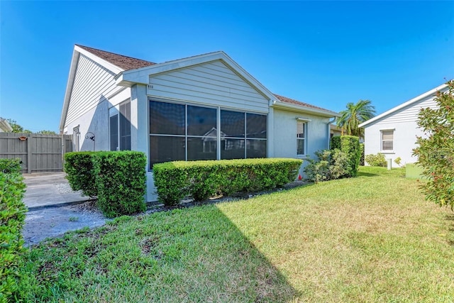 rear view of property featuring a lawn, fence, and a sunroom