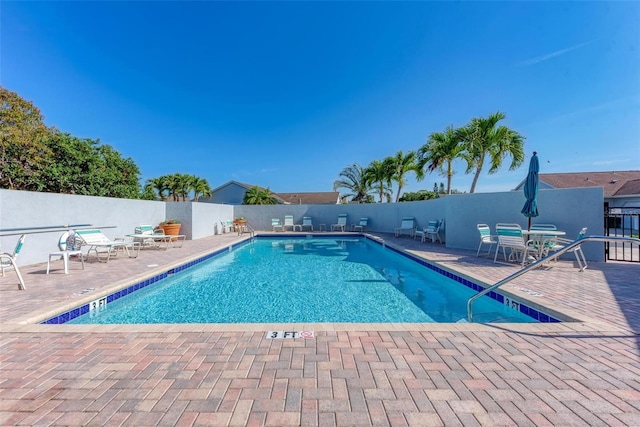 pool with a patio and fence