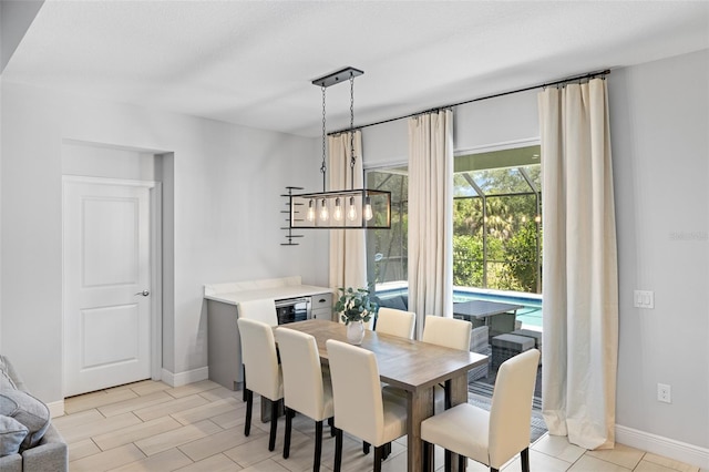 dining area featuring light wood-style flooring, baseboards, and a textured ceiling