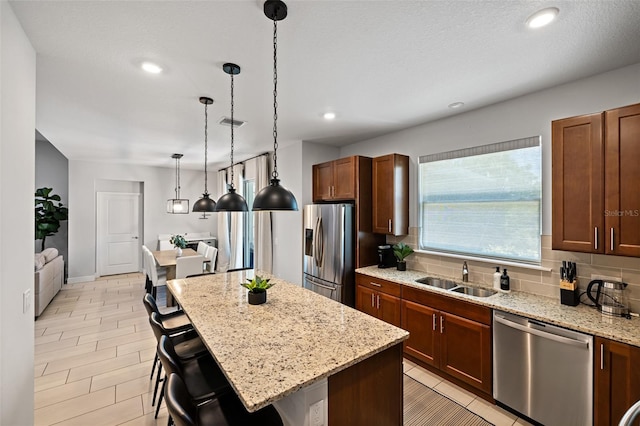 kitchen featuring tasteful backsplash, appliances with stainless steel finishes, a breakfast bar, light stone counters, and a sink