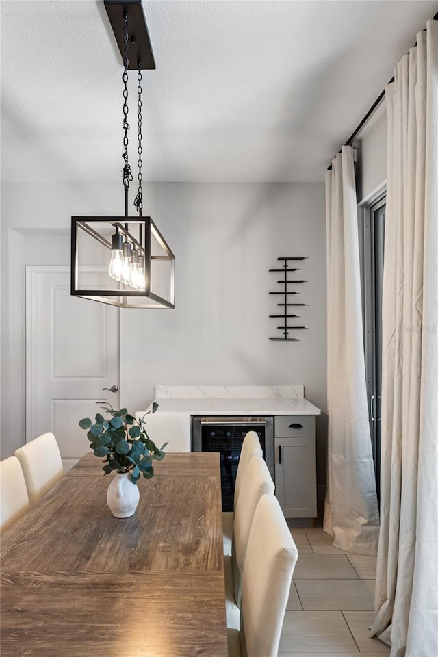 dining room featuring beverage cooler, a bar, and a textured ceiling