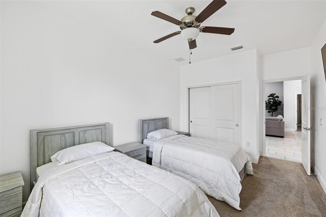 carpeted bedroom featuring ceiling fan, visible vents, and a closet