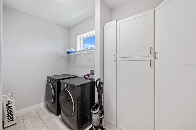 clothes washing area featuring cabinet space, baseboards, and washer and dryer