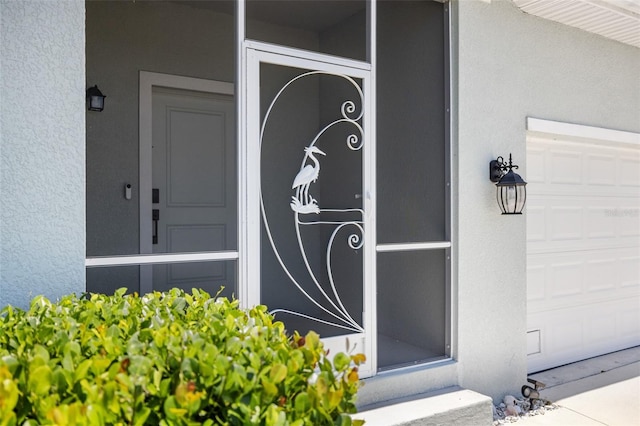 doorway to property with a garage and stucco siding