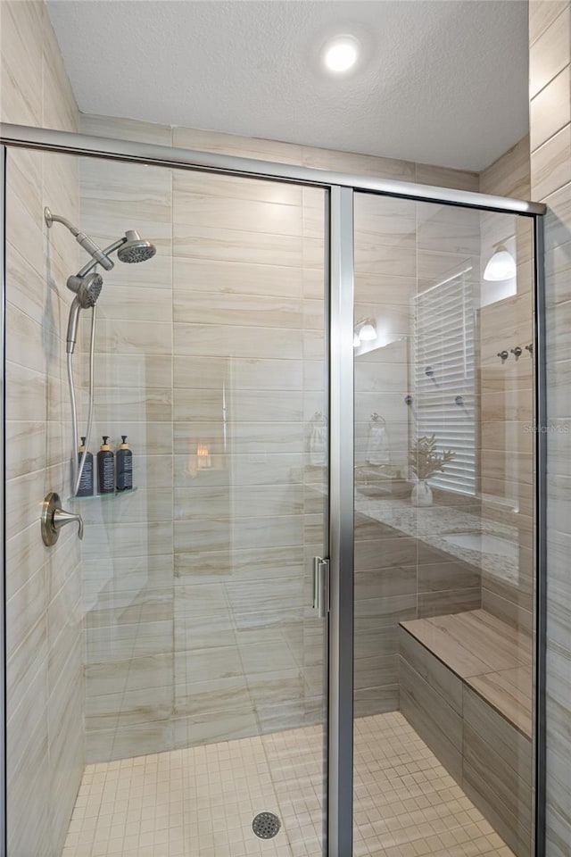 full bath with a textured ceiling and a shower stall