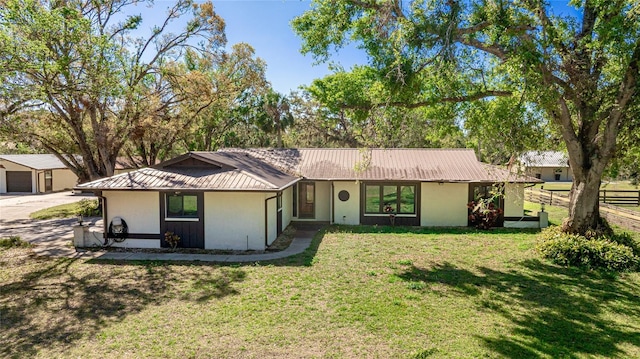 single story home with a standing seam roof, fence, metal roof, and a front yard