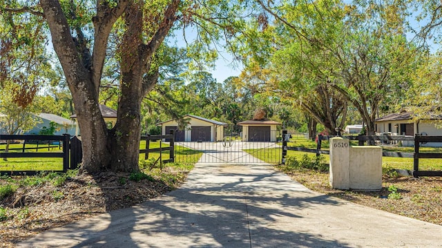 view of front facade with a front lawn, a detached garage, fence, and a gate