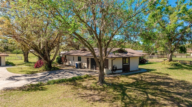 view of front of home featuring a front yard, fence, driveway, and stucco siding