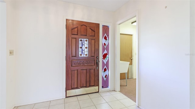 foyer with light carpet, baseboards, and light tile patterned floors