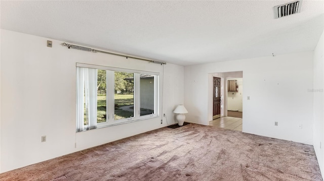 empty room featuring a textured ceiling, carpet, and visible vents