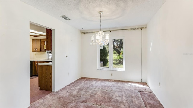 unfurnished dining area with carpet floors, an inviting chandelier, visible vents, and a textured ceiling