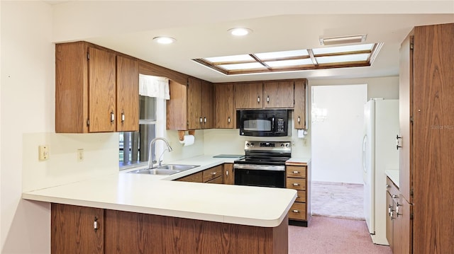 kitchen with freestanding refrigerator, stainless steel range with electric cooktop, a sink, black microwave, and a peninsula