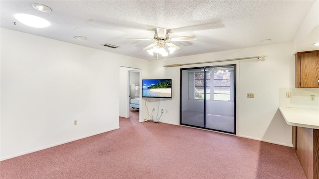 unfurnished living room with carpet floors, a ceiling fan, visible vents, and a textured ceiling