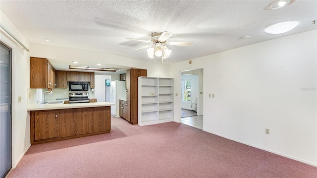 kitchen featuring black microwave, light carpet, a sink, freestanding refrigerator, and stainless steel electric stove