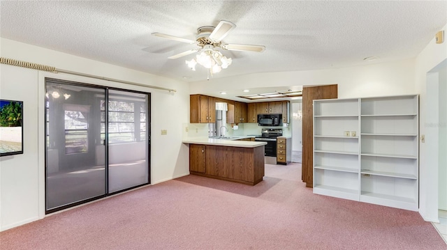 kitchen with electric stove, brown cabinets, a peninsula, light countertops, and black microwave