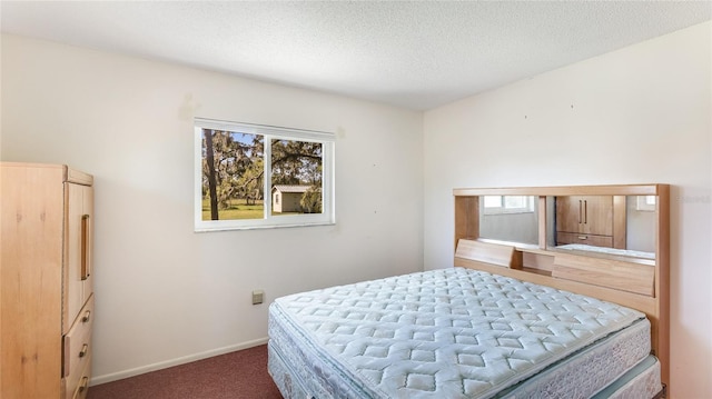 bedroom with a textured ceiling, dark carpet, and baseboards