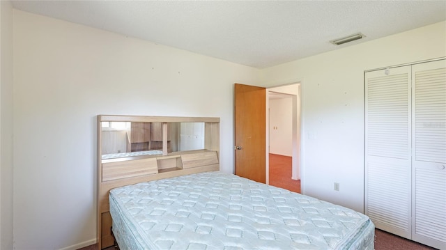 carpeted bedroom with a textured ceiling, a closet, and visible vents