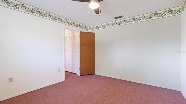 carpeted spare room with baseboards, visible vents, and a ceiling fan