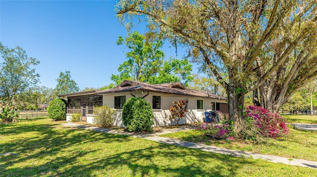 view of side of home featuring fence, a lawn, and stucco siding