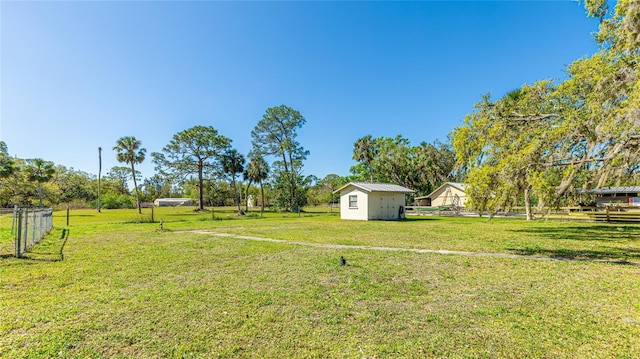 view of yard featuring a shed, an outdoor structure, and fence