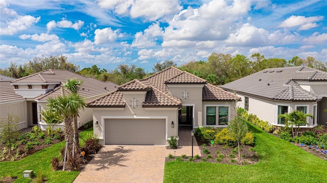 mediterranean / spanish home with a tile roof, an attached garage, decorative driveway, a front lawn, and stucco siding