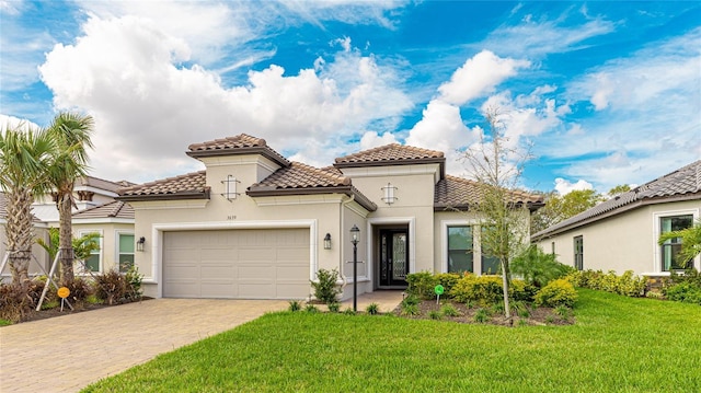 mediterranean / spanish-style house featuring an attached garage, a tiled roof, decorative driveway, stucco siding, and a front lawn