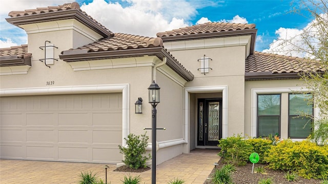 view of front of property with a garage, a tiled roof, and stucco siding