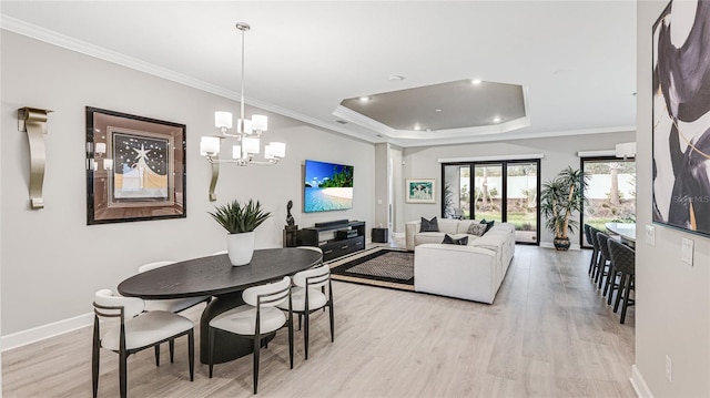 dining space featuring baseboards, a tray ceiling, light wood-style floors, and crown molding