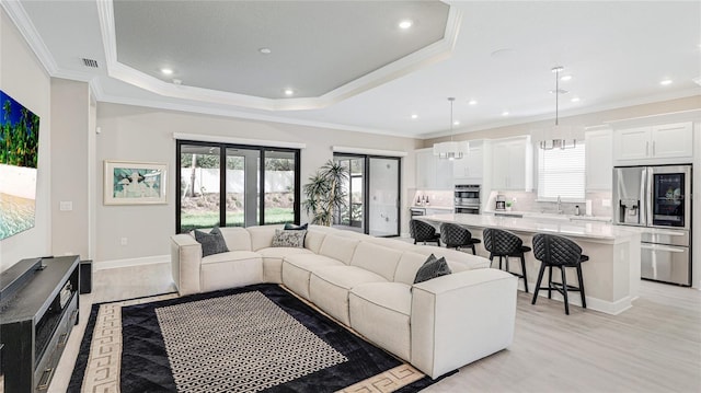 living room with ornamental molding, a raised ceiling, and plenty of natural light